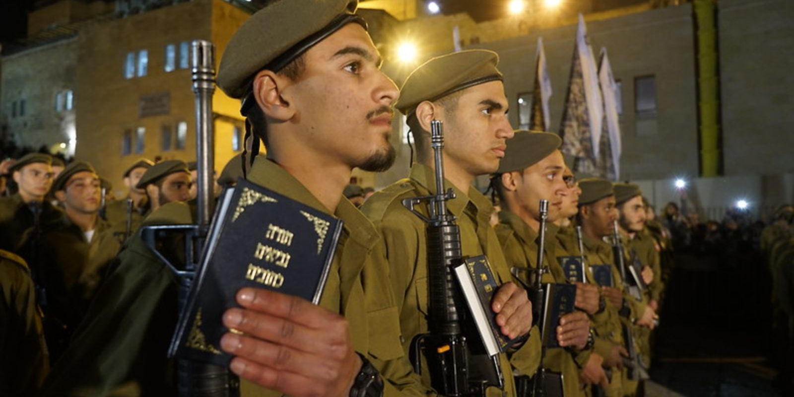IDF soldiers holds guns and copies of the Hebrew Bible at their swearing-in ceremony (Flickr.com)